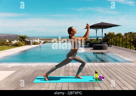 Jeune femme caucasienne pratiquant le yoga et méditant près de la piscine Banque D'Images