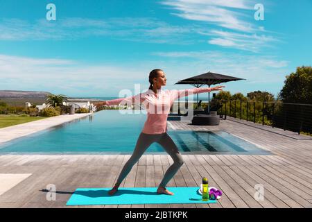 Jeune femme caucasienne pratiquant le yoga et méditant près de la piscine Banque D'Images