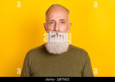 Photo de beau vieux gars sérieux calme look caméra porter chemise vert isolé couleur jaune arrière-plan Banque D'Images