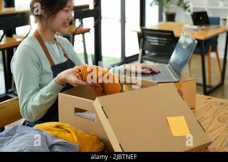 Une femme freelance vendeuse prépare une boîte de colis de produit à livrer au client à domicile. Vente en ligne, e-commerce, emballage, expédition, nouvelle norme Banque D'Images