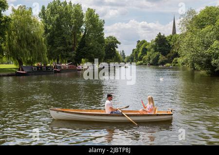 Un couple assis dans un bateau à rames, la femme prend une photo de l'homme au téléphone ou peut-être prend un selfie. Instagram, Facebook, concept de blogging. Banque D'Images