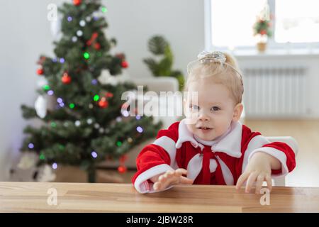 Enfant fille vêtue d'une robe de noël avec implants cochléaires s'amusant à la maison - diversité et aide auditive et technologies innovantes pour le traitement Banque D'Images