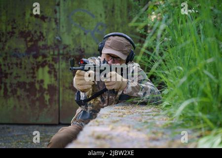 Entraînement de combat du soldat des forces spéciales. Homme dans les munitions militaires se tiennent en garde. L'homme militaire se cache en position avec l'arme dans les mains. Ranger pendant l'opération militaire. Banque D'Images