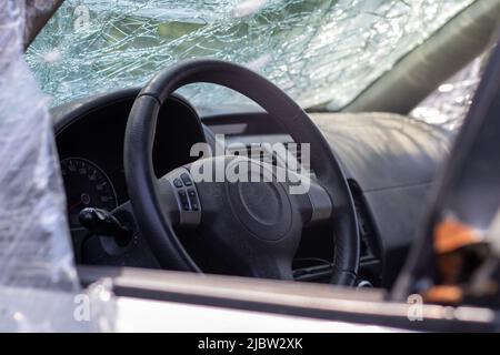 Le volant d'une voiture après un accident. Les airbags conducteur ne se sont pas déployés. Vue depuis la fenêtre de gauche. Pare-brise cassé avec direction wh Banque D'Images