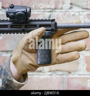 main d'homme dans un gant tactique tenir la poignée avant pour un fusil de tir. Pistolet à main prêt à l'emploi. Tireur prêt à frapper la cible en tenant la main. Banque D'Images