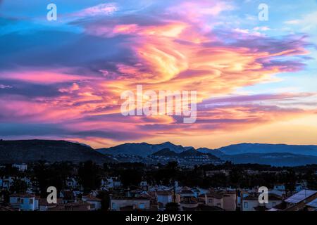 Denia Espagne coucher de soleil avec des nuages colorés et lumineux étonnants au-dessus des montagnes Banque D'Images