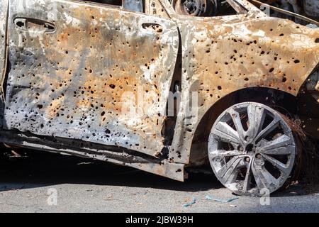 Carrosserie brûlée criblée de balles. La guerre de la Russie contre l'Ukraine. Tiré par la voiture militaire russe de civils pendant l'évacuation. Traces de taureau Banque D'Images