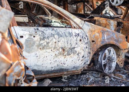 Carrosserie brûlée criblée de balles. La guerre de la Russie contre l'Ukraine. Tiré par la voiture militaire russe de civils pendant l'évacuation. Traces de taureau Banque D'Images