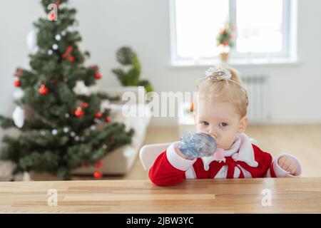 Enfant fille vêtue d'une robe de noël avec implants cochléaires s'amusant à la maison - diversité et aide auditive et technologies innovantes pour le traitement Banque D'Images