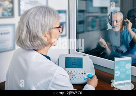 Homme senior qui obtient un test auditif au centre d'audiologie. Audiométrie, contrôle auditif Banque D'Images