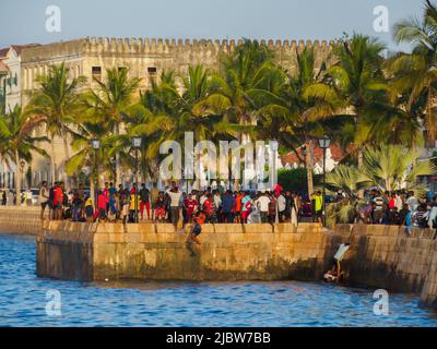 Ville de pierre, Zanzibar, Tanzanie - Jan 2021: Foule des gens sur les jardins de Forodhani et les enfants sautant dans l'eau d'un mur pendant l'heure du coucher du soleil. C Banque D'Images