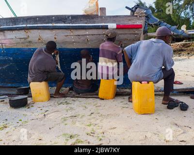 Kizimkazi, Zanzibar - Jan, 2021: Les pêcheurs réparent un bateau traditionnel en bois dhow se tenant sur la rive de l'océan à marée basse. Zanzibar, Tanzanie, Afrique Banque D'Images