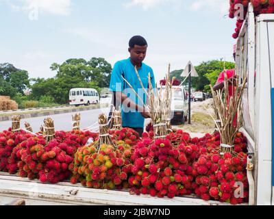 Zanzibar, Tanzanie - Fév, 2021: Beaucoup de grappe de fruits rouges de lychee vendus directement de la voiture sur la rue de l'Afrique. Autres noms connus: Lychee, long Banque D'Images