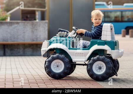 Un jeune garçon dans une voiture à batterie. Le concept d'une enfance heureuse. Banque D'Images