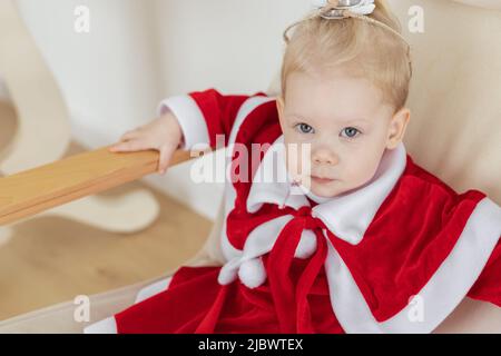 Enfant fille vêtue d'une robe de noël avec implants cochléaires s'amusant à la maison - diversité et aide auditive et technologies innovantes pour le traitement Banque D'Images