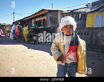 Ilakaka, Madagascar - 30 avril 2019: Inconnu pauvre enfant malgache debout dans la rue, portant chaud hiver veste, chapeau et foulard donné par touri Banque D'Images