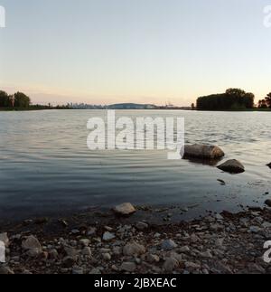 Rive avec la ville au loin au coucher du soleil Banque D'Images