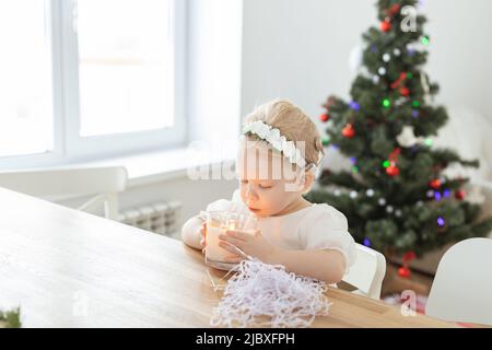 Enfant fille vêtue d'une robe de noël avec implants cochléaires s'amusant à la maison - diversité et aide auditive et technologies innovantes pour le traitement Banque D'Images