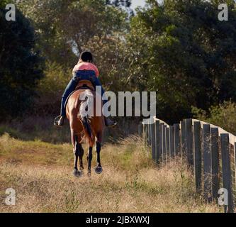 Vue arrière de la jeune femme cantering cheval à travers le Bush australien Banque D'Images
