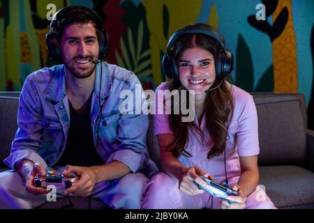 Deux amis jouant à des jeux vidéo avec des micro-casques Banque D'Images