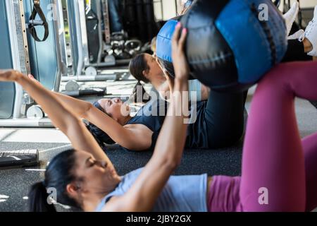Femme déterminée en classe de forme physique en salle de gym faisant un visage douloureux pendant la classe avec poids de balle de médecine. Banque D'Images