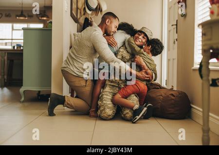 Accueil militaire joyeux. Une femme soldat se réunirait avec son mari et ses enfants après avoir servi dans l'armée. Servicewoman embrassant sa famille Banque D'Images