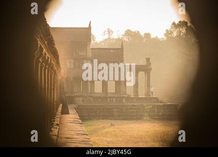 Une vue inhabituelle à travers une fenêtre qui regarde le long d'une galerie d'Angkor Wat au lever du soleil Banque D'Images