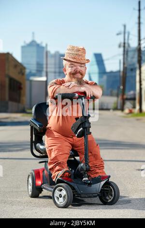 Portrait de nain masculin assis sur un scooter, regardant dans l'appareil photo avec un grand sourire. Banque D'Images