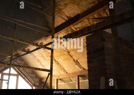 Le toit de forme complexe est isolé avec de la laine de verre jaune et de la laine minérale verte. Technologie d'isolation de toit. Échafaudage. Banque D'Images