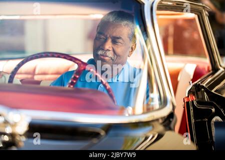 Homme plus âgé assis au siège du conducteur de la berline sport Super 88 Holiday 1960 d'Oldsmobile Banque D'Images