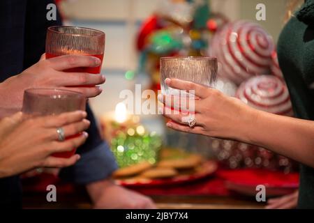 Détail de Groupe d'amis tenant des lunettes punch à la fête de Noël avec des décorations de vacances Banque D'Images