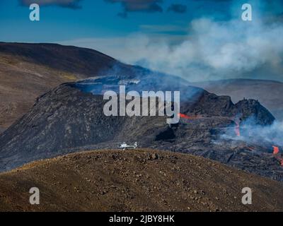 Photo aérienne, des hélicoptères atterrissent sur la colline d'observation près du cratère de Fagradalsfjall, éruption volcanique à Geldingadalir, Islande Banque D'Images