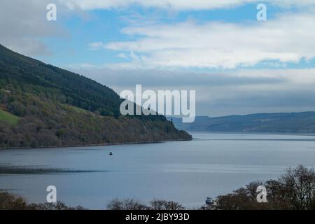 Vue panoramique sur le Loch Ness en Écosse avec montagnes et fond bleu ciel, et végétation au premier plan Banque D'Images