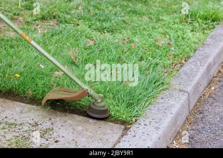 L'employé coupe l'herbe à l'aide d'un coupe-ficelle sur de l'essence Banque D'Images