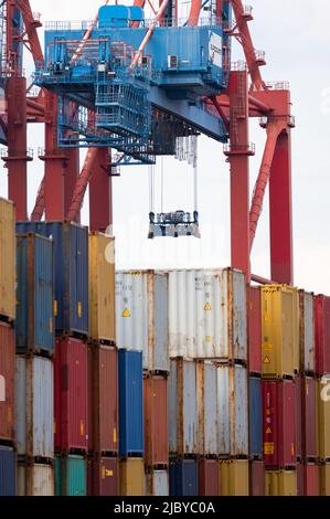 Hambourg, Allemagne. 08th juin 2022. La pince d'une grue à portique pour conteneurs qui n'est pas en service est suspendue sur des piles de conteneurs à un terminal à conteneurs de Waltershof. Pour la première fois depuis des décennies, une grève d'avertissement des dockers dans les principaux ports maritimes allemands menace de mettre les navires à l'arrêt. Credit: Jonas Walzberg/dpa/Alay Live News Banque D'Images