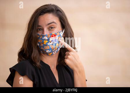 Femme caucasienne portant un masque en tissu pointant sur un autocollant J'ai voté aujourd'hui sur le masque Banque D'Images