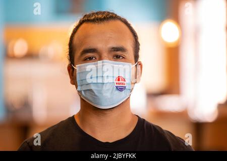 Portrait intérieur d'un homme hispanique portant un masque et un autocollant J'ai voté aujourd'hui sur le masque Banque D'Images