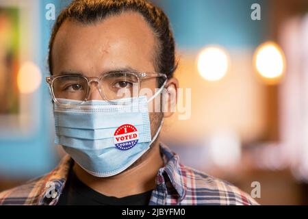 Portrait intérieur d'un homme hispanique portant un masque et un autocollant J'ai voté aujourd'hui sur le masque Banque D'Images