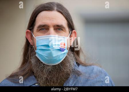 Portrait d'un homme caucasien avec de longs cheveux et une barbe complète portant un masque et un autocollant J'ai voté aujourd'hui sur le masque Banque D'Images