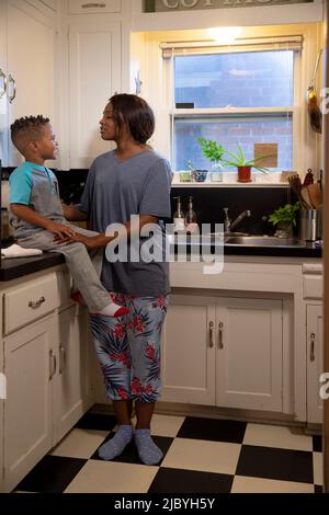 Maman à la maison dans la cuisine ayant une discussion avec son fils assis sur le comptoir Banque D'Images