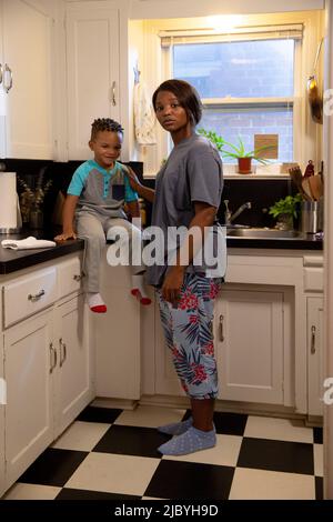 Maman à la maison dans la cuisine avec son fils assis sur le comptoir Banque D'Images