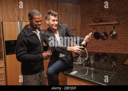 Gay couple drinking wine in kitchen Banque D'Images