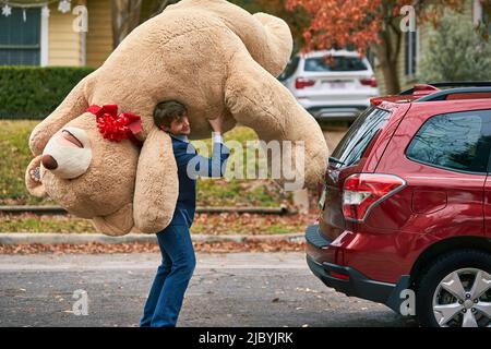 Gros plan d'un homme tenant un ours en peluche sur son épaule. Banque D'Images