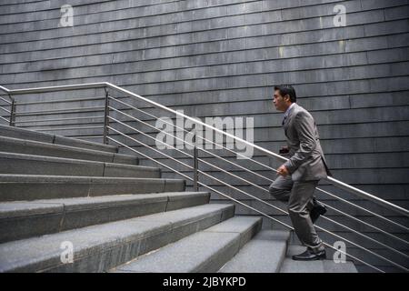 Chinese businessman running up stairs Banque D'Images