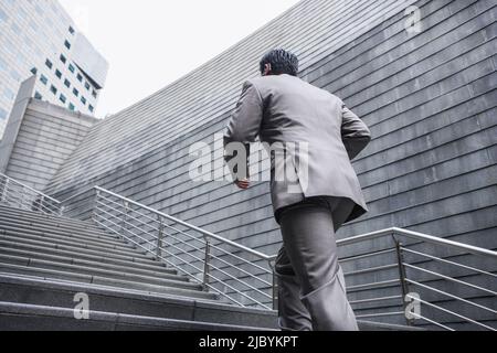 Chinese businessman running up stairs Banque D'Images