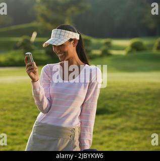 Pilipino golfeur text messaging on cell phone Banque D'Images