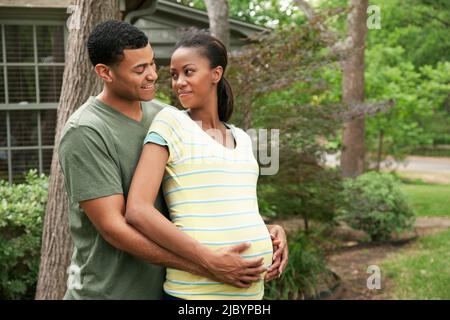 Homme embrassant la femme enceinte dans la cour Banque D'Images