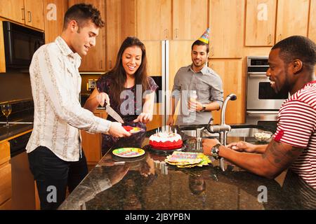 Amis ayant gâteau d'anniversaire dans la cuisine Banque D'Images