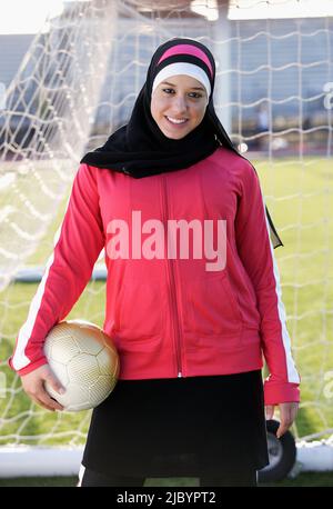 Adolescente musulmane holding soccer ball Banque D'Images