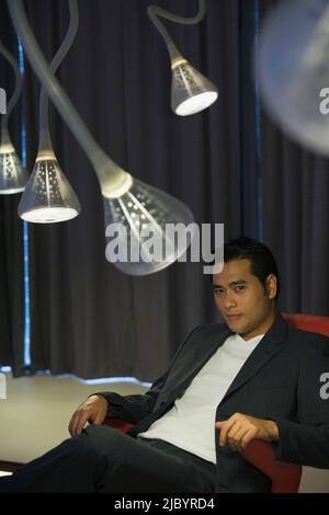 Chinese man sitting in modern living room Banque D'Images